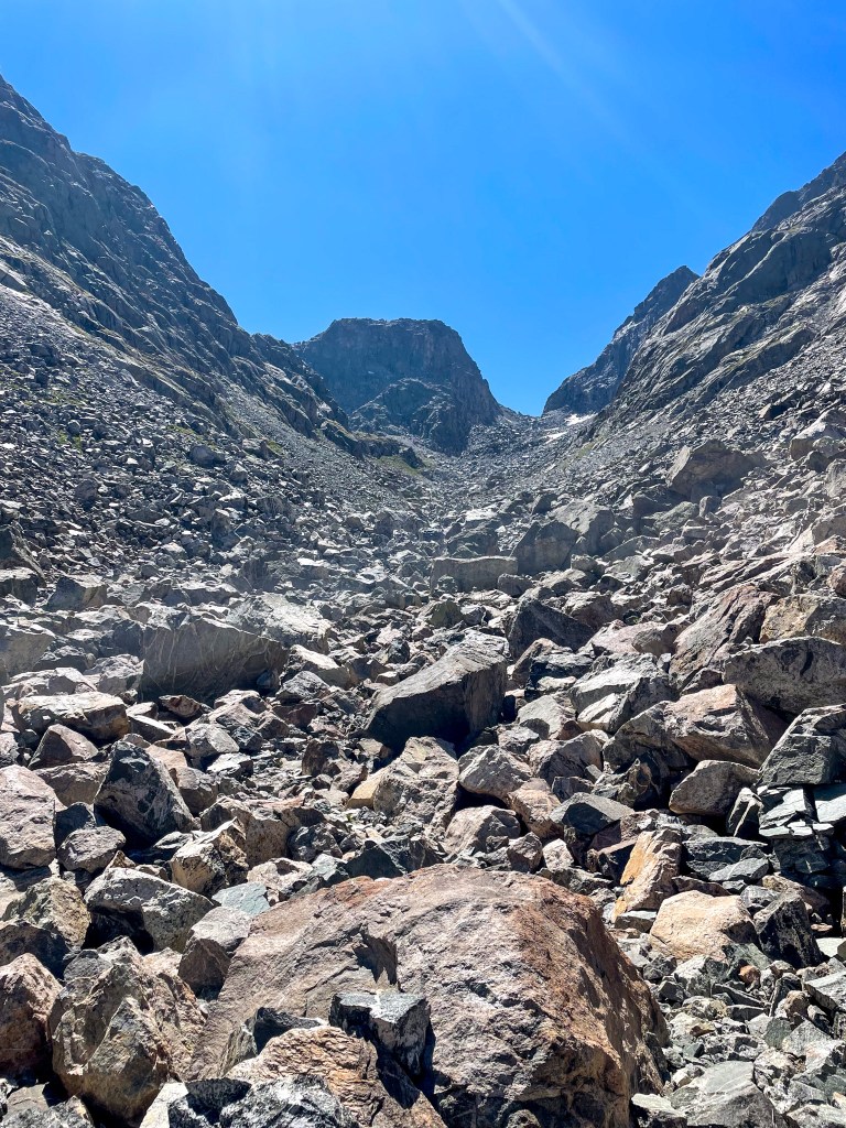 A rocky mountain landscape with steep sides and a clear blue sky overhead.
